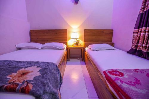 a bedroom with two beds and a lamp on a table at Hotel Muna International Residential 6th floor in Dhaka