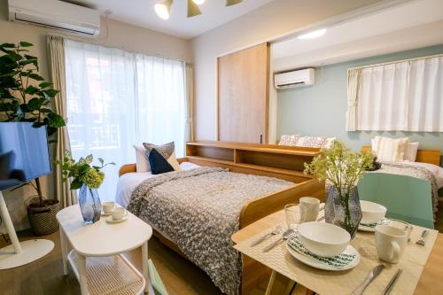 a bedroom with a bed and a table and a tv at Premium Apartment Hotel Tokyo East in Tokyo