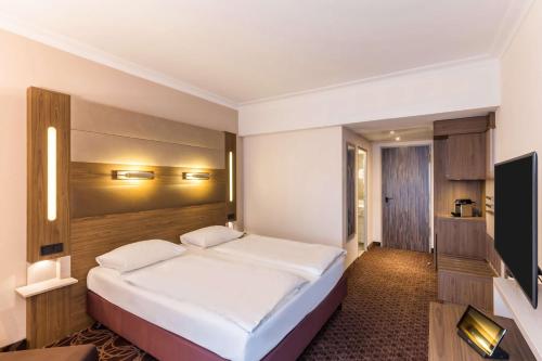 a bedroom with a large white bed and a television at Best Western Plus Hotel Koeln City in Cologne
