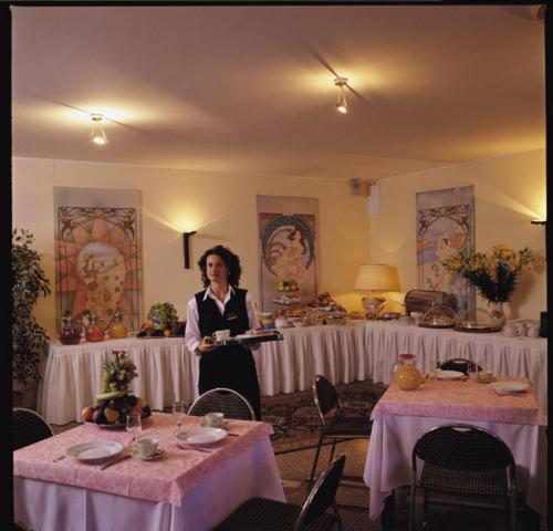 a woman standing in a room with two tables at Hotel & Loisir Le Ruote in Roveleto