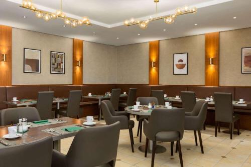 ein Restaurant mit Tischen und Stühlen in einem Raum in der Unterkunft Ramada by Wyndham Duesseldorf Ratingen in Ratingen
