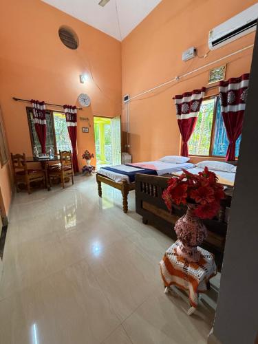 a bedroom with two beds and a vase with flowers in it at Native Homestay in Gokarna