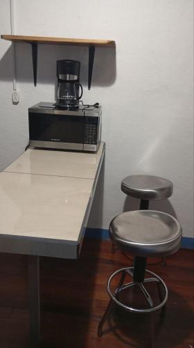 a counter with a coffee maker and two stools at Hostel Casa Ridgway in San José