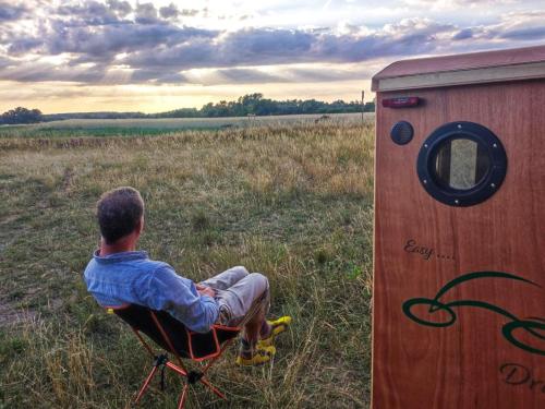 a boy sitting in a chair next to a outhouse at Tinydorf XXS in Sinsheim