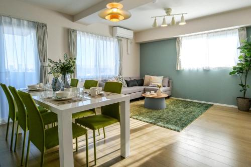a living room with a white table and green chairs at Premium Apartment Hotel Tokyo East in Tokyo