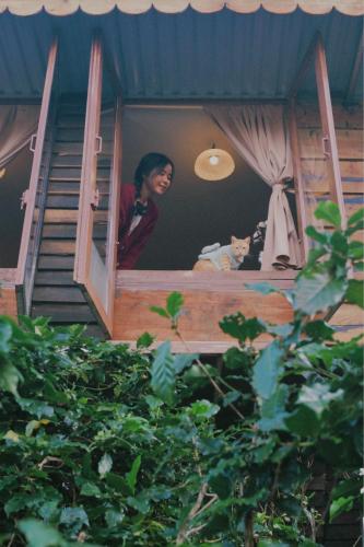 a woman looking out the window of a house at Cú Trên Cây Homestay in Xuan An