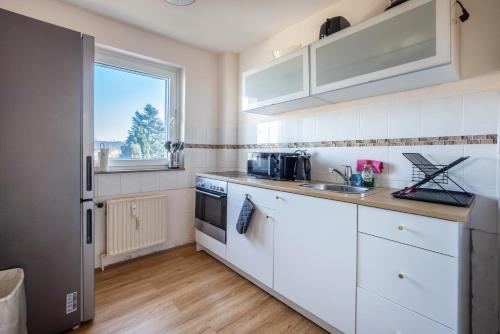 a kitchen with white cabinets and a window at Fewo Danzing in Quickborn