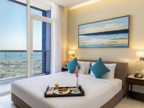 a hotel room with a bed with a tray of food on it at Swiss-Belsuites Admiral Juffair in Manama