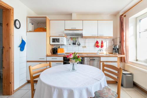 a kitchen with a table with a vase of flowers on it at Hus Tingeltut Gerd Clausen in Pellworm