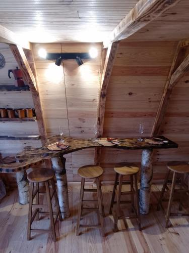 Chambre avec 2 tables et tabourets dans une cabane en rondins dans l'établissement D'tente skylodge SKALI, à Massat