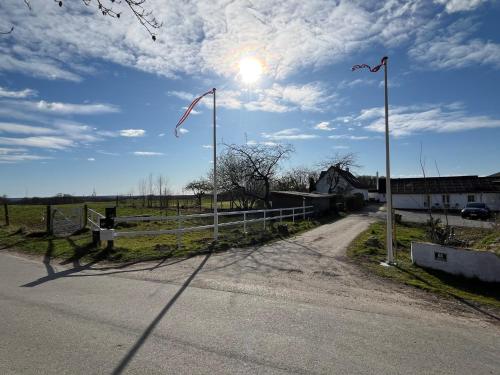 a road with a fence and a kite flying in the sky at Bakkely in Hjortshøj