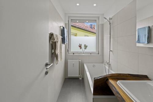 a bathroom with a tub and a sink and a window at Golden Stay Residence in Brunn am Gebirge