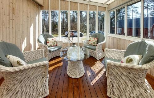 a screened porch with wicker chairs and a glass table at Nice Home In Vittsjö With Sauna in Vittsjö