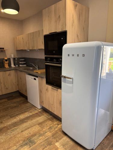 - un réfrigérateur blanc dans une cuisine avec des placards en bois dans l'établissement Au Bois Dormant, à Huby-Saint-Leu