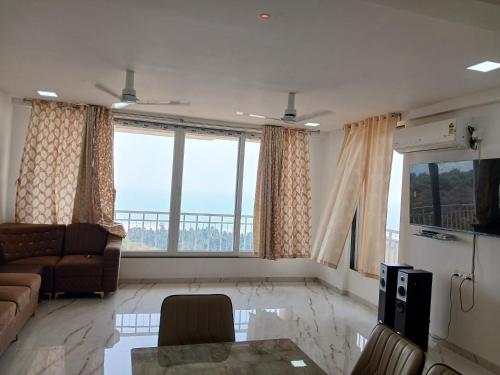 a living room with a couch and a large window at Nikhat villa 61 in Harnai