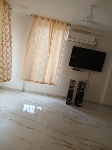 a living room with a flat screen tv and two speakers at Nikhat villa 61 in Harnai