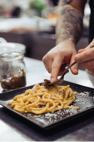 a person eating pasta on a plate with a fork and knife at Agriturismo La Sapienza in Monestirolo
