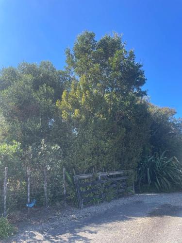 a wooden fence in front of some trees at Cosy Country Private Cottage with views in Harapepe