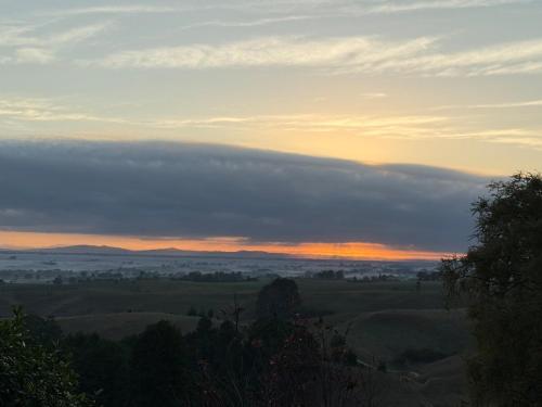 a view of a field at sunset with clouds at Cosy Country Private Cottage with views in Harapepe