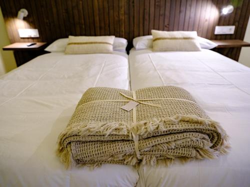 two beds in a hotel room with white sheets at Hotel Rural Casa del Oso in El Oso