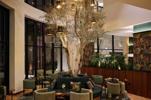 a lobby with chairs and a tree in the middle at The Muse in Doha