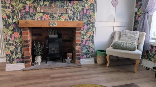 a living room with a fireplace and a chair at Captains Cottage in Scarborough