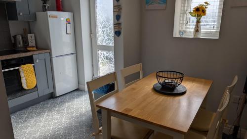 a kitchen with a wooden table with chairs and a refrigerator at Captains Cottage in Scarborough