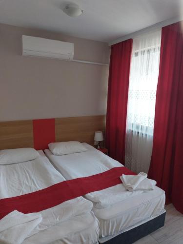 a bedroom with two beds and a window with red curtains at ТЕС Боровец Гарденс in Borovets