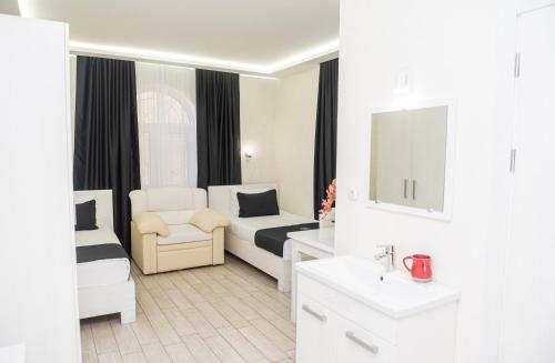 a white room with a bed and a chair and a sink at Hoshen Hotel in Umanʼ