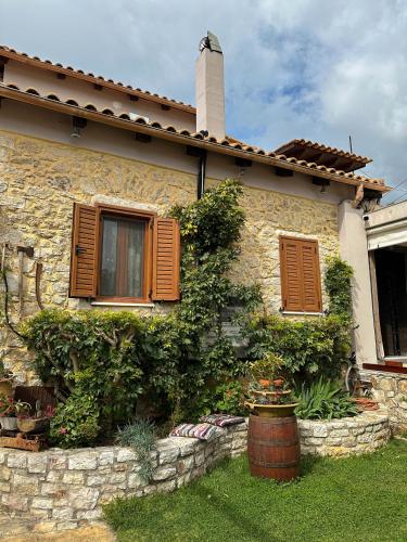 a stone house with brown windows and a stone wall at Villa Eva's in Himare