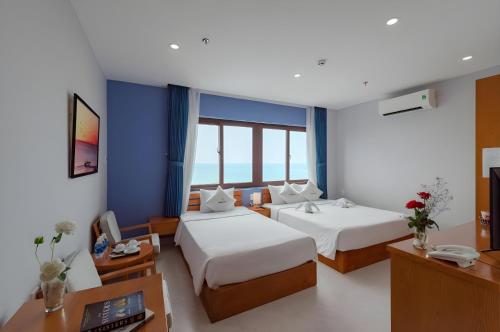 a hotel room with two beds and a desk at Stellar Phú Quốc - Hotel in Phu Quoc