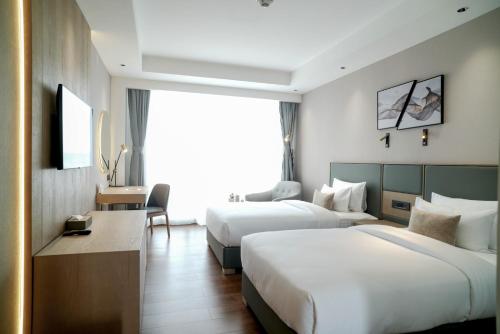 a hotel room with two beds and a television at Aurum by R J Resorts in Siliguri