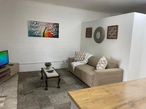 una sala de estar con un sofá y una mesa en Baybreeze Flatlet, en Ciudad del Cabo