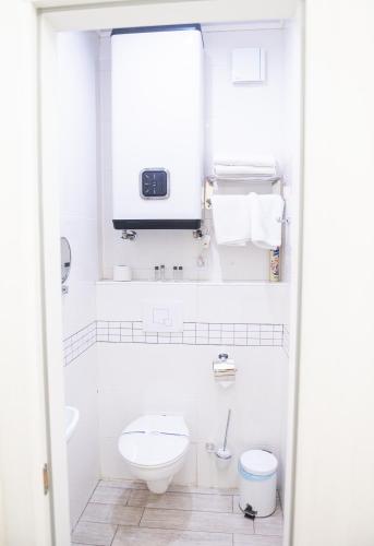 a white bathroom with a toilet and a sink at Hoshen Hotel in Umanʼ