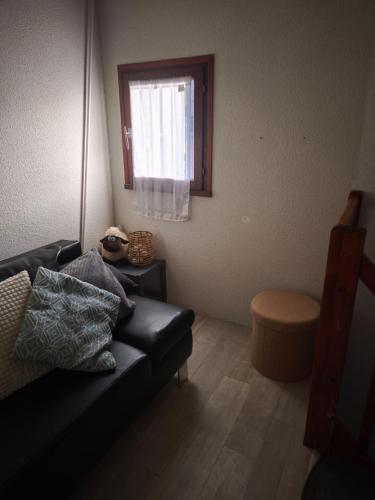 - un salon avec un canapé noir et une fenêtre dans l'établissement Maison grande terrasse proche du port St Cyprien, à Saint-Cyprien