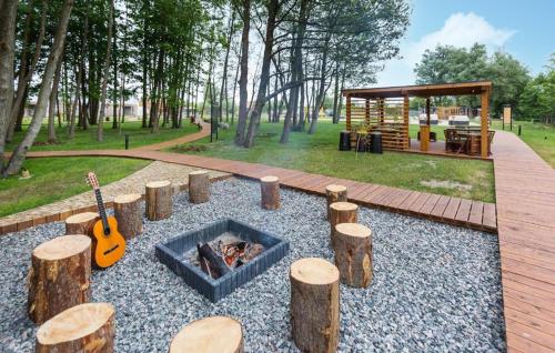 a fire pit with logs and a guitar in a park at Amazing Home In Niechorze With Sauna in Niechorze