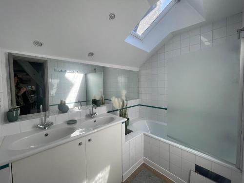 La salle de bains blanche est pourvue d'un lavabo et d'une baignoire. dans l'établissement L 'escale de st patern, à Vannes