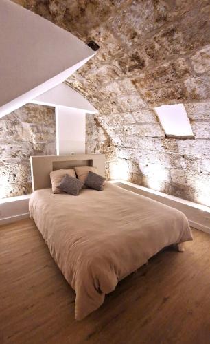 une chambre avec un grand lit avec un mur en pierre dans l'établissement Les bons Enfants 9, à Rouen