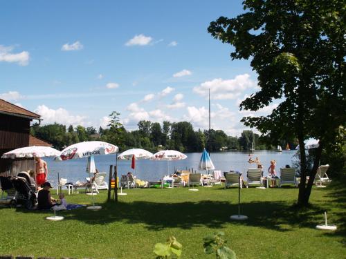 a group of people sitting on the grass near a lake at Eichenhof in Waging am See