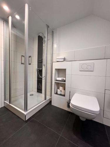 a white bathroom with a shower and a toilet at Hotel Restaurant Wolfsschlucht GmbH in Bad Münstereifel