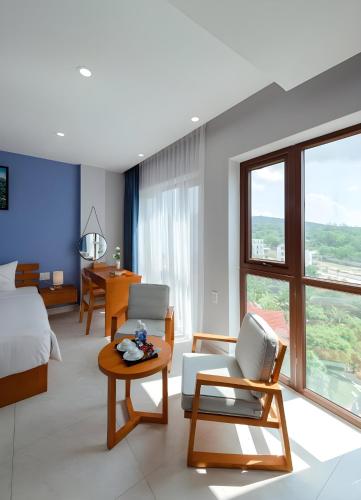 a hotel room with a bed and a table and chairs at Stellar Phú Quốc - Hotel in Phu Quoc