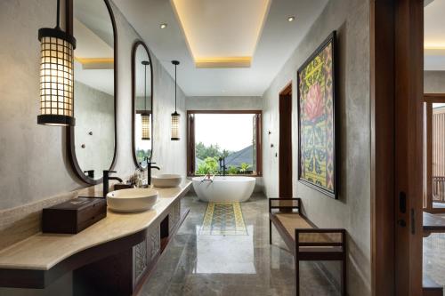 a bathroom with two sinks and a large mirror at Inara Alas Harum in Ubud