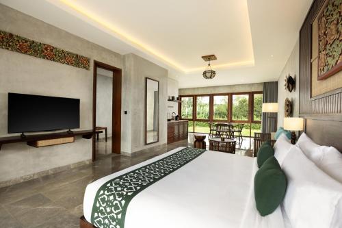 a bedroom with a large white bed and a flat screen tv at Inara Alas Harum in Ubud