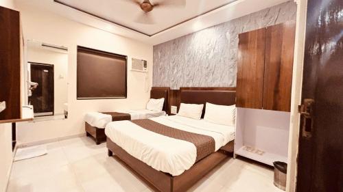 ein Hotelzimmer mit zwei Betten und einem Fernseher in der Unterkunft Hotel Garden Palace in Mumbai