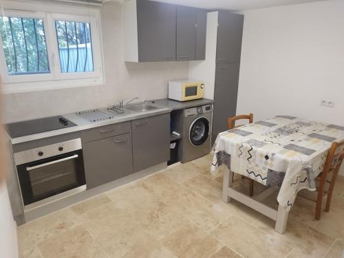 - une cuisine avec une table, une cuisinière et un évier dans l'établissement L'ensoleillé, à Aubagne