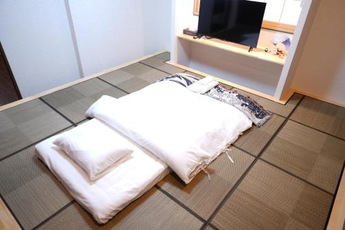 a bed sitting on the floor in front of a tv at ohayo両国 in Tokyo