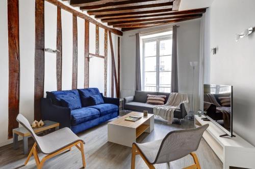 un salon avec un canapé bleu et des chaises dans l'établissement BnBNova - 1BR - Saint Germain & Buci, à Paris