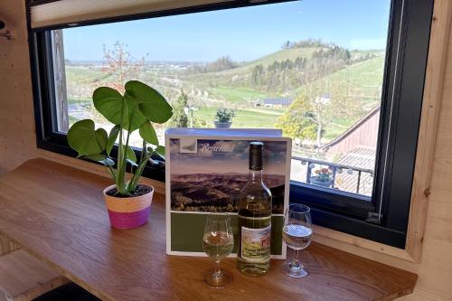 a bottle of wine and two glasses on a table with a window at Weingut und Ferienhof Josef Huber in Oberkirch