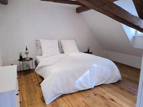 een slaapkamer met een wit bed en houten vloeren bij Scheunenromantik Altstadt in Forchheim