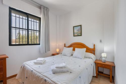 a bedroom with a large white bed with towels on it at Apto Unifamiliar Dos Dormitorios in Chiclana de la Frontera